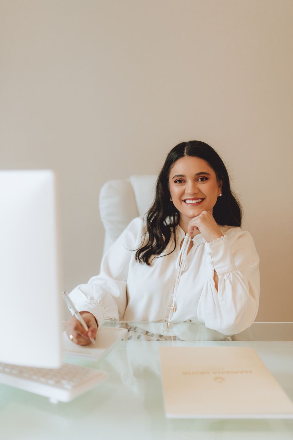 Dra. Mariana Motta sorrindo à mesa do consultório