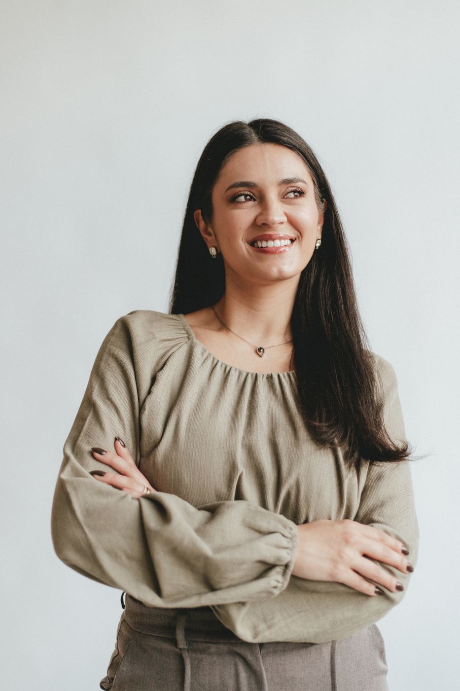 Dra. Mariana Motta sorrindo, de blusa verde-oliva e braços cruzados